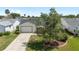 Inviting single-story home with manicured lawn, mature trees, and a palm-lined driveway at 604 Ellsworth Way, The Villages, FL 32162