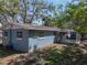 Side exterior of blue block home with a covered patio and large trees creating shade at 501 15Th Ne Ct, Winter Haven, FL 33881