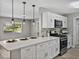 Bright kitchen featuring white cabinets, stainless steel appliances, and a quartz countertop island at 501 15Th Ne Ct, Winter Haven, FL 33881