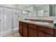 Well-lit bathroom with a double sink vanity and tiled shower at 1413 Wallace Manor Pass, Winter Haven, FL 33880