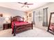 Bedroom with a large wood-framed bed, ceiling fan, neutral carpet, and natural light from the window at 6898 Sw 95Th Cir, Ocala, FL 34481