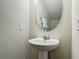 A clean and modern half bath with a pedestal sink, mirror, and neutral tones for a sleek and functional design at 3926 Grassland Dr, Orlando, FL 32824