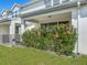 Rear exterior featuring a covered patio framed by vibrant flowering plants and green grass at 3926 Grassland Dr, Orlando, FL 32824