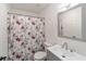 Bathroom features white sink and vanity, gray-trimmed mirror, and toilet with a floral shower curtain at 39832 N Hibiscus Way, Lady Lake, FL 32159