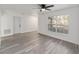 Open living room featuring a ceiling fan, gray wood-look flooring, and a window overlooking an American flag at 39832 N Hibiscus Way, Lady Lake, FL 32159