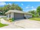 Exterior of the home featuring a large garage door and well maintained lawn and landscaping at 1007 Cr 463B, Lake Panasoffkee, FL 33538
