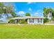 Charming single-story home featuring a well-manicured lawn, complemented by lush landscaping and a welcoming yellow front door at 1007 Cr 463B, Lake Panasoffkee, FL 33538