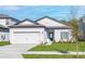 Charming single-story home featuring a well-manicured lawn, a two-car garage, and a striking blue front door at 13284 Tula Loop, Astatula, FL 34705