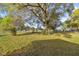A large backyard features mature shade trees and lush green grass at 5728 Ne 21St Avenue Rd, Ocala, FL 34479