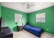 Bright bedroom featuring a ceiling fan, neutral tile flooring, and ample natural light from two windows at 5728 Ne 21St Avenue Rd, Ocala, FL 34479