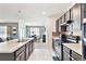Well-lit kitchen features stainless appliances, dark cabinets and a view into the dining room at 879 Killarney Ln, Auburndale, FL 33823