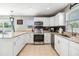 Well-lit kitchen featuring white cabinets, granite countertops, stainless steel appliances, and backyard access at 4523 Oakglen Rd, Lakeland, FL 33813