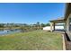 Lawn slopes gently toward a pond, framed by lush greenery, offering a tranquil backyard at 1762 Regal River Cir, Ocoee, FL 34761