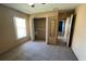 Bedroom with tan carpet and walls, ceiling fan, large window, closet and small mirror at 1124 Liberty Hall Dr, Kissimmee, FL 34746