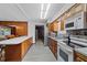 Galley kitchen showcasing stainless steel appliances, wood cabinets and backsplash, plus an island with seating at 1203 Lake Miriam Dr, Lakeland, FL 33813