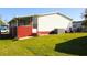 Back exterior view with grass, painted white with red trim, and central air conditioning unit at 2514 Sea Oats N Cir, Lakeland, FL 33815