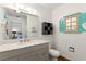 Well-lit bathroom featuring a stylish vanity, toilet, decorative accent decor, and a bright window with turquoise shutters at 2971 Gardenia Dr, Indian Lake Estates, FL 33855