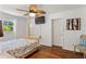 A bedroom with wood flooring, a window overlooking trees, and a ceiling fan, with a TV mounted on the wall at 2971 Gardenia Dr, Indian Lake Estates, FL 33855