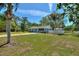 Charming home featuring a well-maintained lawn, mature trees, white picket fence, and an outbuilding at 2971 Gardenia Dr, Indian Lake Estates, FL 33855