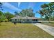 Charming single-story home with a well-maintained front lawn, mature trees, and a welcoming entrance at 2971 Gardenia Dr, Indian Lake Estates, FL 33855