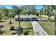 Charming single-story home with a well-manicured lawn, mature trees, and a long driveway leading to the house at 2971 Gardenia Dr, Indian Lake Estates, FL 33855