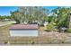Aerial view of the metal outbuilding with brown roof, fenced in yard and lush green trees at 2971 Gardenia Dr, Indian Lake Estates, FL 33855