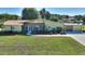 Aerial view of the home with green lawn, manicured landscaping, and a canal in the back at 6365 Avocado Dr, Indian Lake Estates, FL 33855