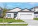 Attractive single-story home featuring manicured lawn, blue front door, and two-car garage at 13279 Tula Loop, Astatula, FL 34705