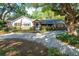 Charming home featuring a brick facade, lush landscaping, a blue front door, and a circular driveway at 1905 Seminole Trl, Lakeland, FL 33803