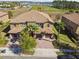 Stunning aerial view of a home featuring a tile roof, three-car garage, lush landscaping, and a brick-paved driveway at 8983 Azalea Sands Ln # 8983, Davenport, FL 33896