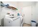 Efficient laundry room with modern washer and dryer, upper shelving, and white door at 319 Bailey Cir, Davenport, FL 33897