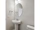 Neutral powder room featuring a pedestal sink, oval mirror, and chrome hardware at 5932 Bristle Oak St, Mount Dora, FL 32757