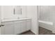 Bathroom vanity with white cabinets, white countertop, large mirror, and view of tiled shower at 1802 White Elephant Loop, Winter Haven, FL 33884