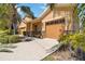 Charming home exterior with a well-manicured lawn, mature landscaping, and attached two-car garage with decorative stone accents at 1892 Sanderling Dr, Clermont, FL 34711