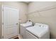 Functional laundry room with white washer and dryer, wire shelving, and a white door at 1892 Sanderling Dr, Clermont, FL 34711
