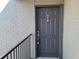 Front door to unit 206, featuring a gray painted door and brick wall, accented by a black metal handrail at 3700 Idlebrook Cir # 206, Casselberry, FL 32707