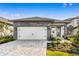 Charming home featuring a gray stone facade, a white garage door, and a brick paver driveway at 7701 Somersworth Dr, Kissimmee, FL 34747