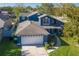 Aerial view of a two-story blue home with an attached garage and lush green lawn at 14610 Astina Way, Orlando, FL 32837