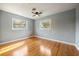 Cozy bedroom featuring hardwood floors, a ceiling fan, and two windows overlooking the yard at 1326 Se 34Th Ter, Ocala, FL 34471