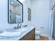 Bathroom featuring wood cabinet, marble countertop, decorative mirror, and tile shower at 829 E Lime St, Lakeland, FL 33801
