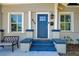 Inviting front porch and blue door featuring updated hardware, seating area, and fresh flowers at 829 E Lime St, Lakeland, FL 33801