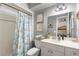 Bathroom with a white vanity, toilet, shower with themed curtain, and seaside artwork at 934 W Heron Cir, Winter Haven, FL 33884