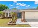 Inviting single-story home with landscaped walkway, a blue front door, and a spacious two-car garage at 934 W Heron Cir, Winter Haven, FL 33884