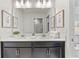 Bathroom vanity featuring double sinks, dark cabinets, and wall decor at 1568 Maidstone Ct, Davenport, FL 33896