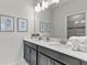 Bright bathroom with double sinks, gray cabinets, and decorative wall art at 1568 Maidstone Ct, Davenport, FL 33896