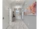Hallway with white floors, light gray walls, and decorative artwork leading to a front door and several rooms at 1568 Maidstone Ct, Davenport, FL 33896