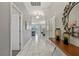 Hallway with white floors and light gray walls leading to the living room and dining room with a decorative mirror at 1568 Maidstone Ct, Davenport, FL 33896