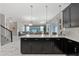 Open-concept kitchen with a large island, dark cabinets, light countertops, and a view to the living and dining areas at 1568 Maidstone Ct, Davenport, FL 33896