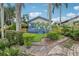 Lush backyard with palm trees, greenery, a charming porch, and a brick path at 515 Frank Lloyd Wright Way, Lakeland, FL 33803