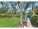Green backyard features palm trees, a privacy fence and a brick path to a detached garage at 515 Frank Lloyd Wright Way, Lakeland, FL 33803